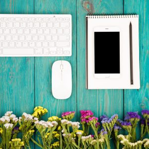 Flowers, mouse, and keyboard on a green wooden surface.