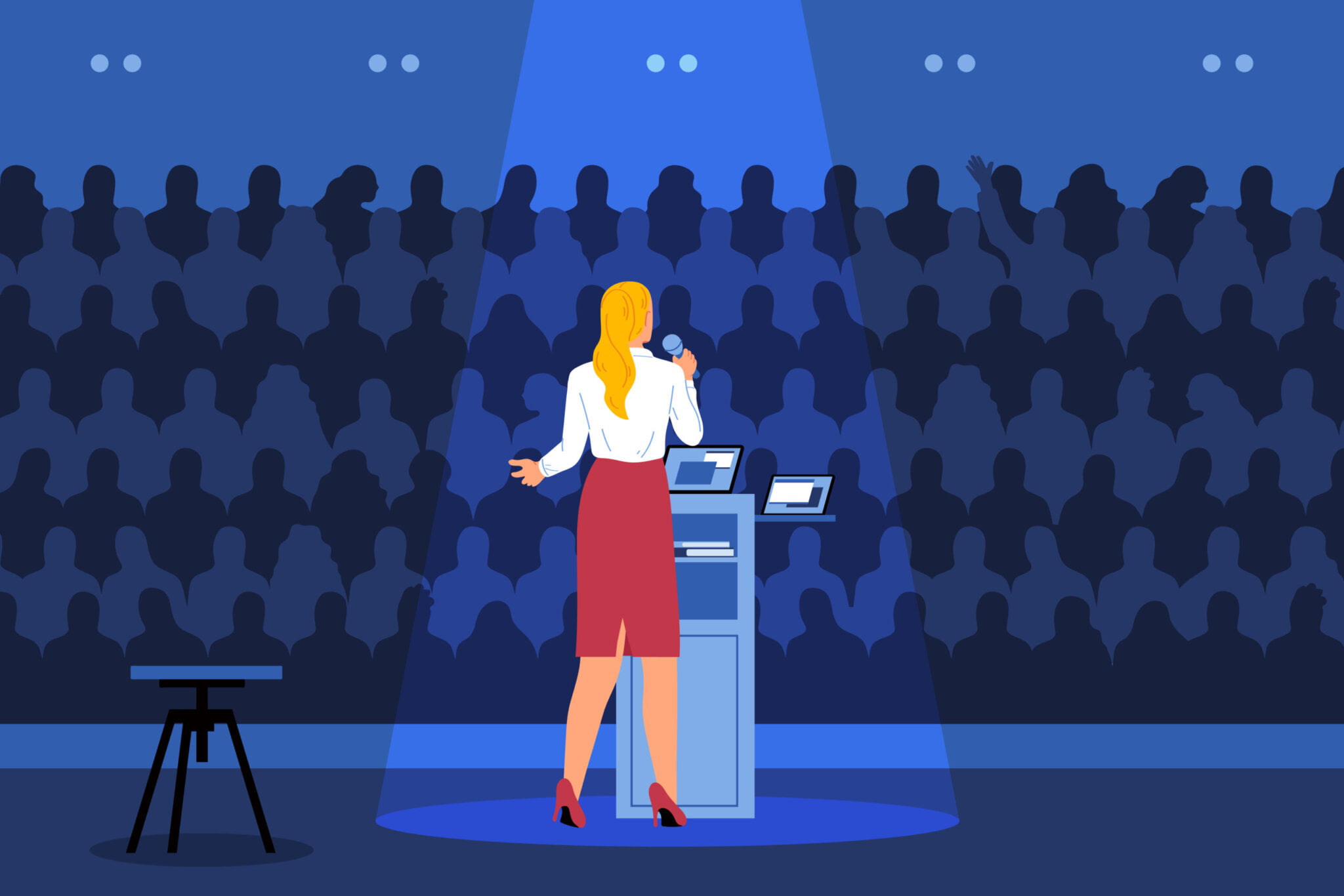 Woman standing at podium before an audience holding a microphone