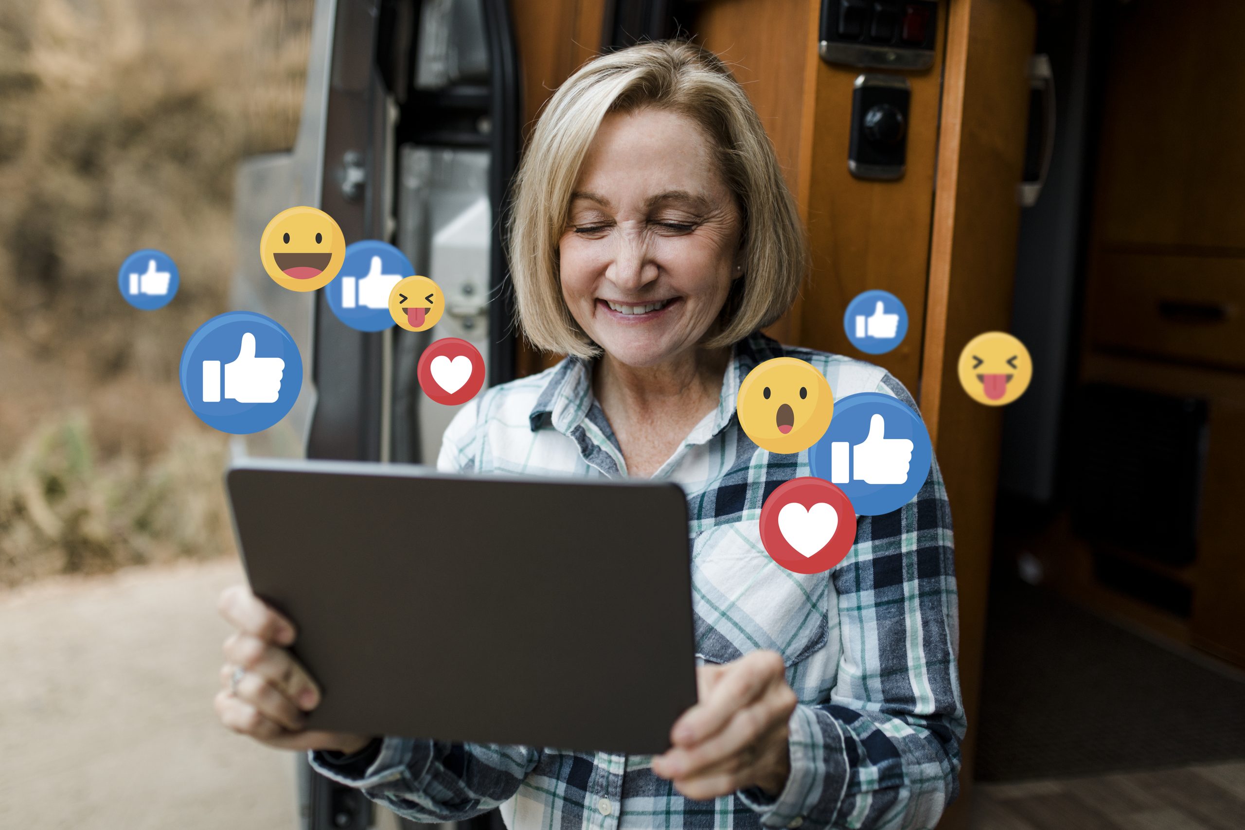 Woman enjoying social media browsing on tablet with social media reaction symbols around her