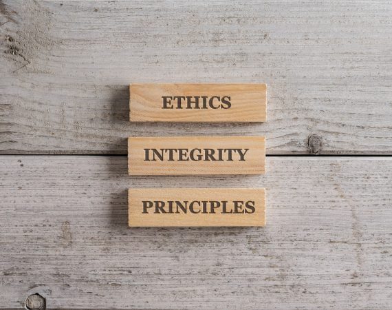 Words Ethics, Integrity and Principles written on three stacked wooden blocks placed over white wooden background.