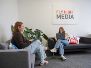 Two women using laptops on couches